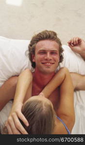 Portrait of a young man and a young woman lying in bed