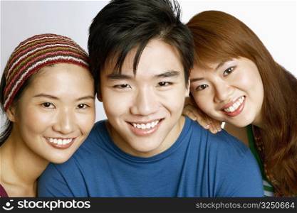 Portrait of a young man and two young women posing and smiling