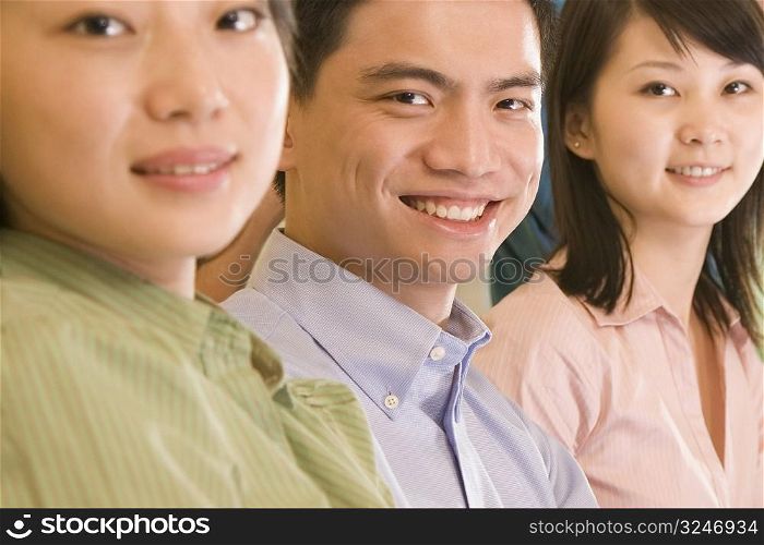 Portrait of a young man and two young women smiling