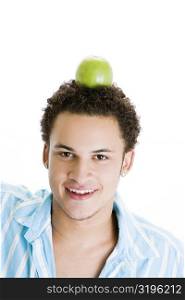 Portrait of a young man balancing a green apple on his head