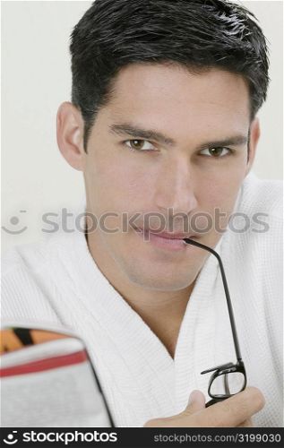 Portrait of a young man biting the shaft of his eyeglasses