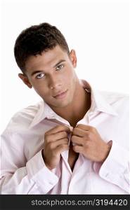 Portrait of a young man buttoning his shirt