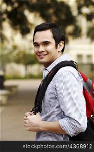 Portrait of a young man carrying a backpack and smiling