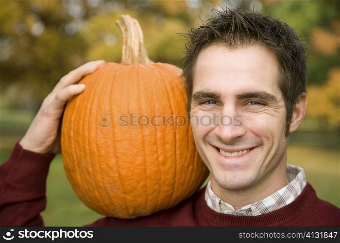 Portrait of a young man carrying a pumpkin and smiling