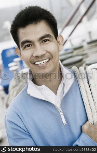 Portrait of a young man carrying a rope over his shoulder and smiling