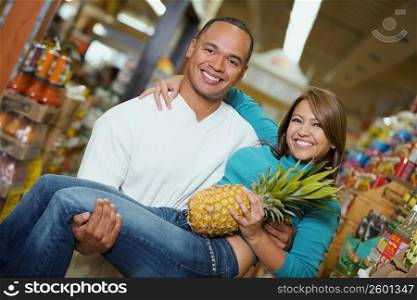 Portrait of a young man carrying a young woman in a supermarket
