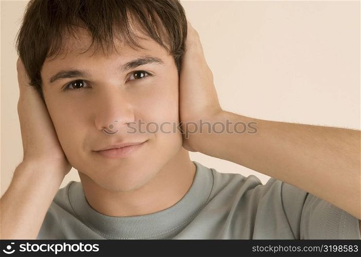 Portrait of a young man covering his ears with his hands