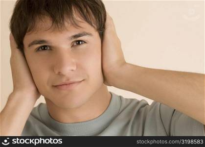 Portrait of a young man covering his ears with his hands