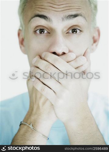 Portrait of a young man covering his mouth with his hands