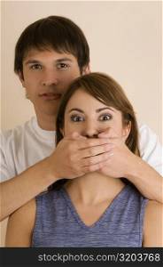 Portrait of a young man covering young woman&acute;s mouth from behind