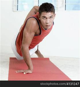 Portrait of a young man doing one hand push-ups on an exercise mat