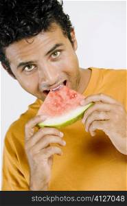Portrait of a young man eating a slice of a watermelon