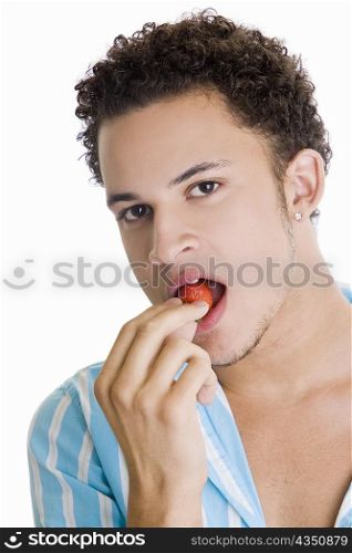 Portrait of a young man eating a strawberry