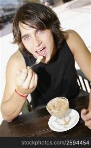 Portrait of a young man eating an ice-cream sundae