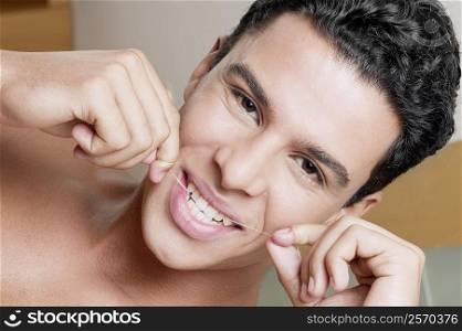 Portrait of a young man flossing his teeth