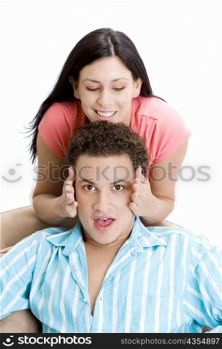 Portrait of a young man getting his face rubbed by a young woman
