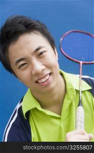 Portrait of a young man holding a badminton racket and smiling