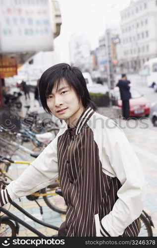 Portrait of a young man holding a bicycle