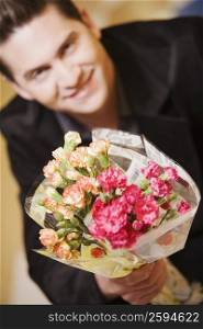 Portrait of a young man holding a bouquet of flowers
