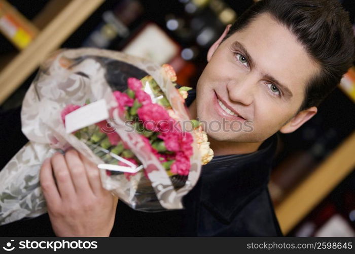 Portrait of a young man holding a bouquet of flowers and smiling