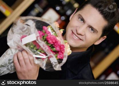 Portrait of a young man holding a bouquet of flowers and smiling