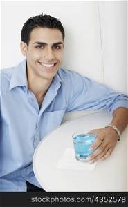 Portrait of a young man holding a cocktail and smiling