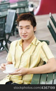 Portrait of a young man holding a coffee cup and a saucer