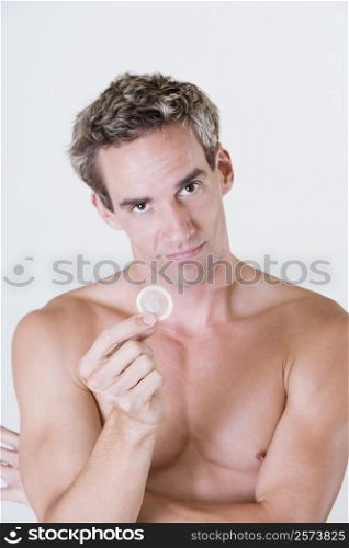 Portrait of a young man holding a condom