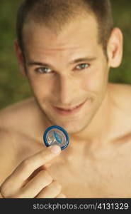 Portrait of a young man holding a condom