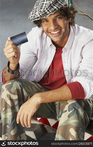 Portrait of a young man holding a credit card and smiling