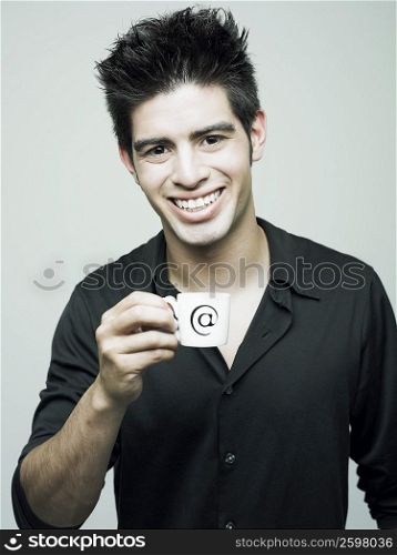 Portrait of a young man holding a cup of tea and smiling