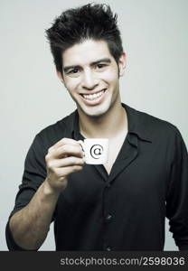 Portrait of a young man holding a cup of tea and smiling