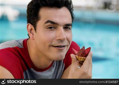 Portrait of a young man holding a cupcake