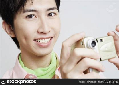Portrait of a young man holding a digital camera