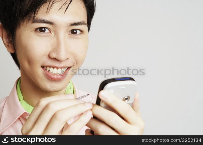 Portrait of a young man holding a digitized pen and a mobile phone