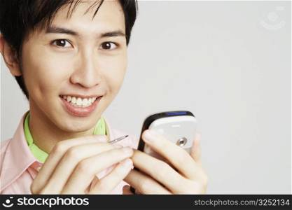Portrait of a young man holding a digitized pen and a mobile phone