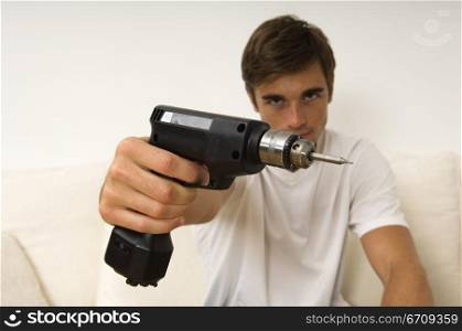 Portrait of a young man holding a drill