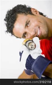 Portrait of a young man holding a drill machine and smiling