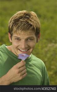 Portrait of a young man holding a flower smiling