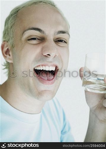 Portrait of a young man holding a glass and laughing