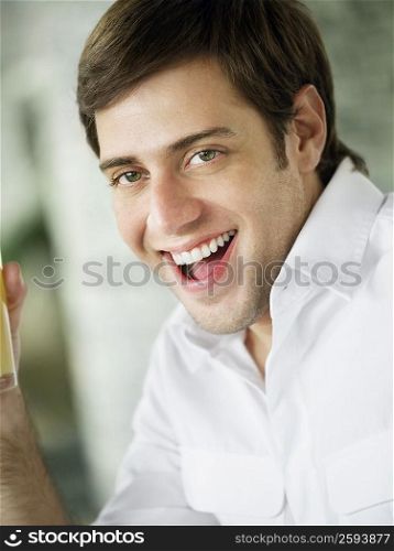Portrait of a young man holding a glass of juice and laughing