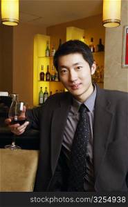 Portrait of a young man holding a glass of red wine