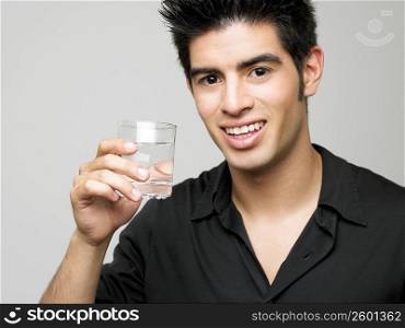 Portrait of a young man holding a glass of water