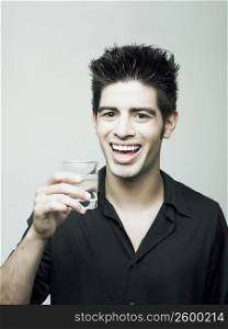Portrait of a young man holding a glass of water and smiling