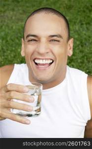 Portrait of a young man holding a glass of water and smiling