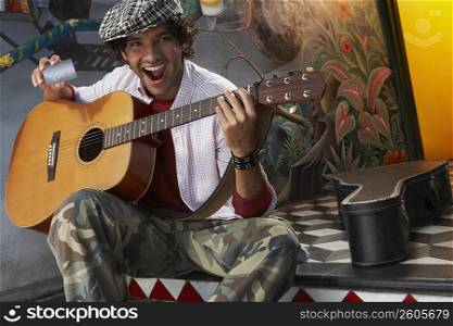 Portrait of a young man holding a guitar and a credit card