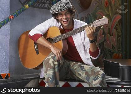 Portrait of a young man holding a guitar and smiling