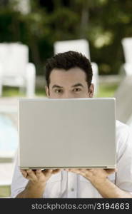 Portrait of a young man holding a laptop