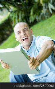 Portrait of a young man holding a laptop and smiling
