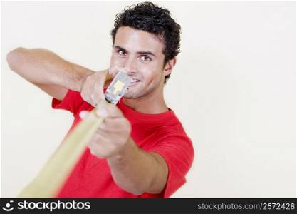Portrait of a young man holding a measuring tape and smiling